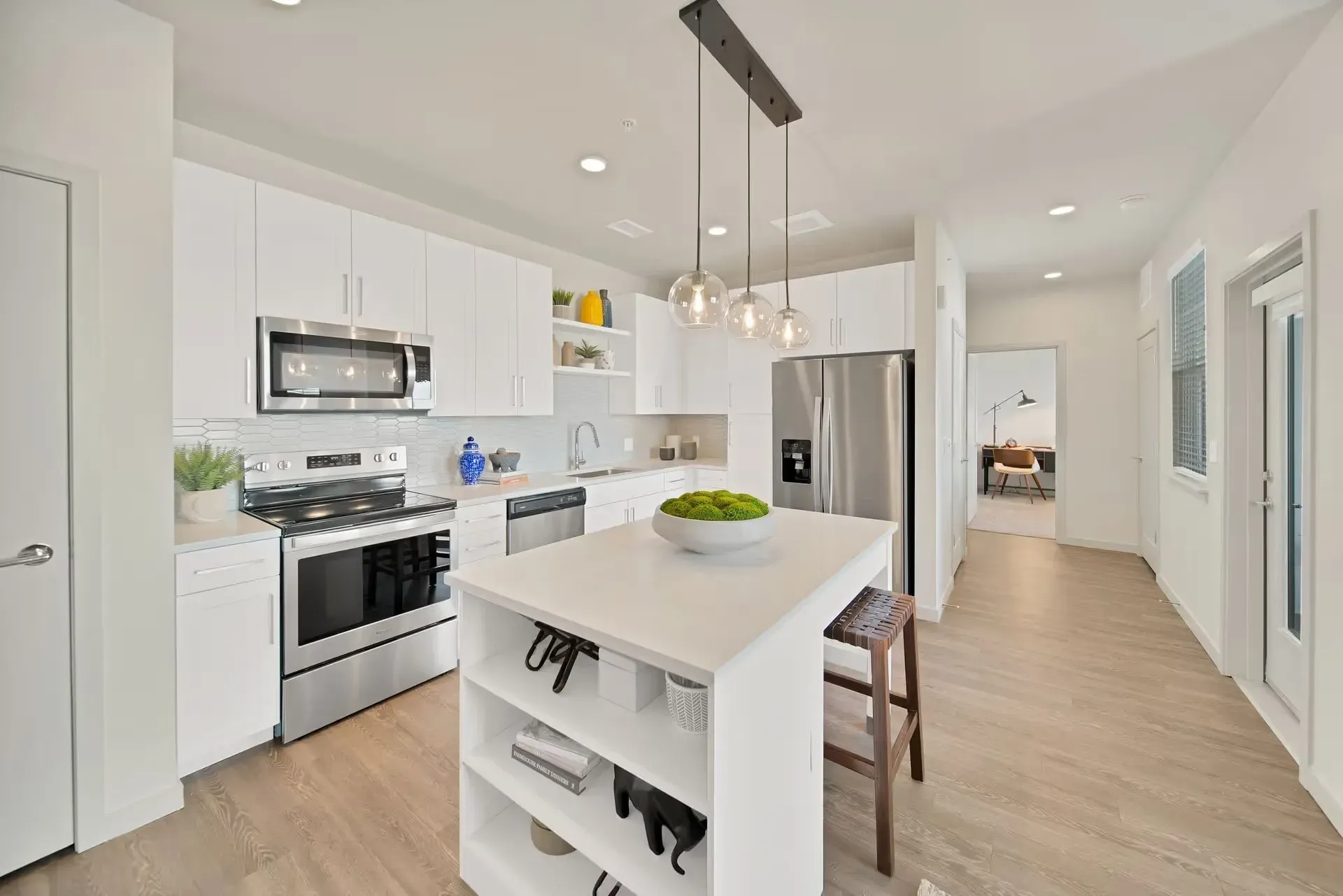Bright modern kitchen with white cabinets, island, stainless appliances, and light wood flooring