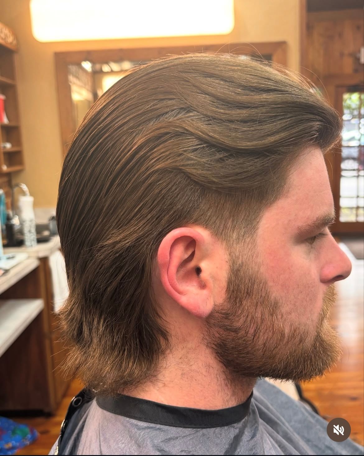 Man with brown hair, fade haircut, and beard, in a barbershop.