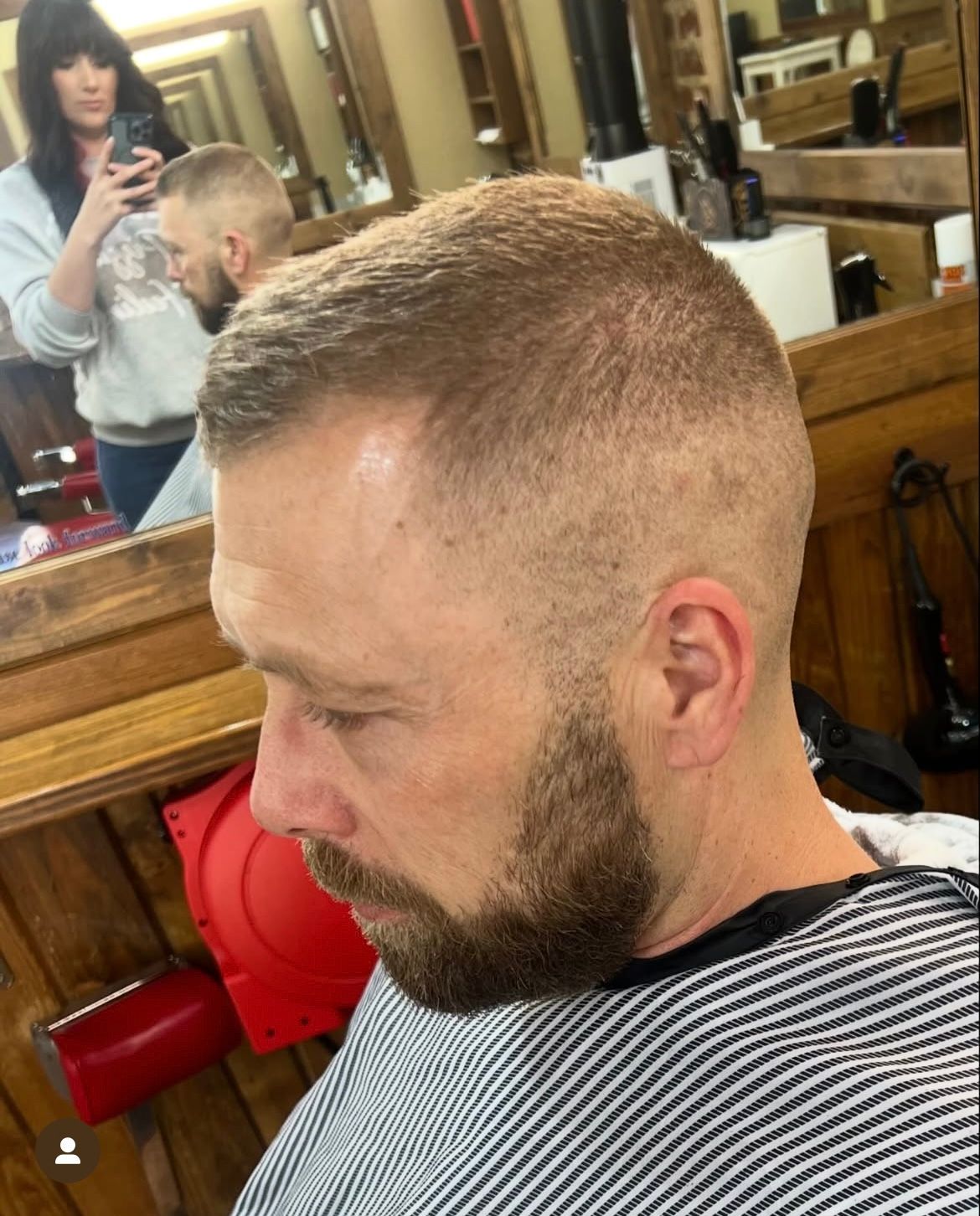 Man with a short haircut and beard in a barbershop, being photographed.