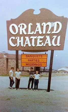 Orland Chateau sign with smaller boards for banquets, parties, and weddings, with three people standing below it.