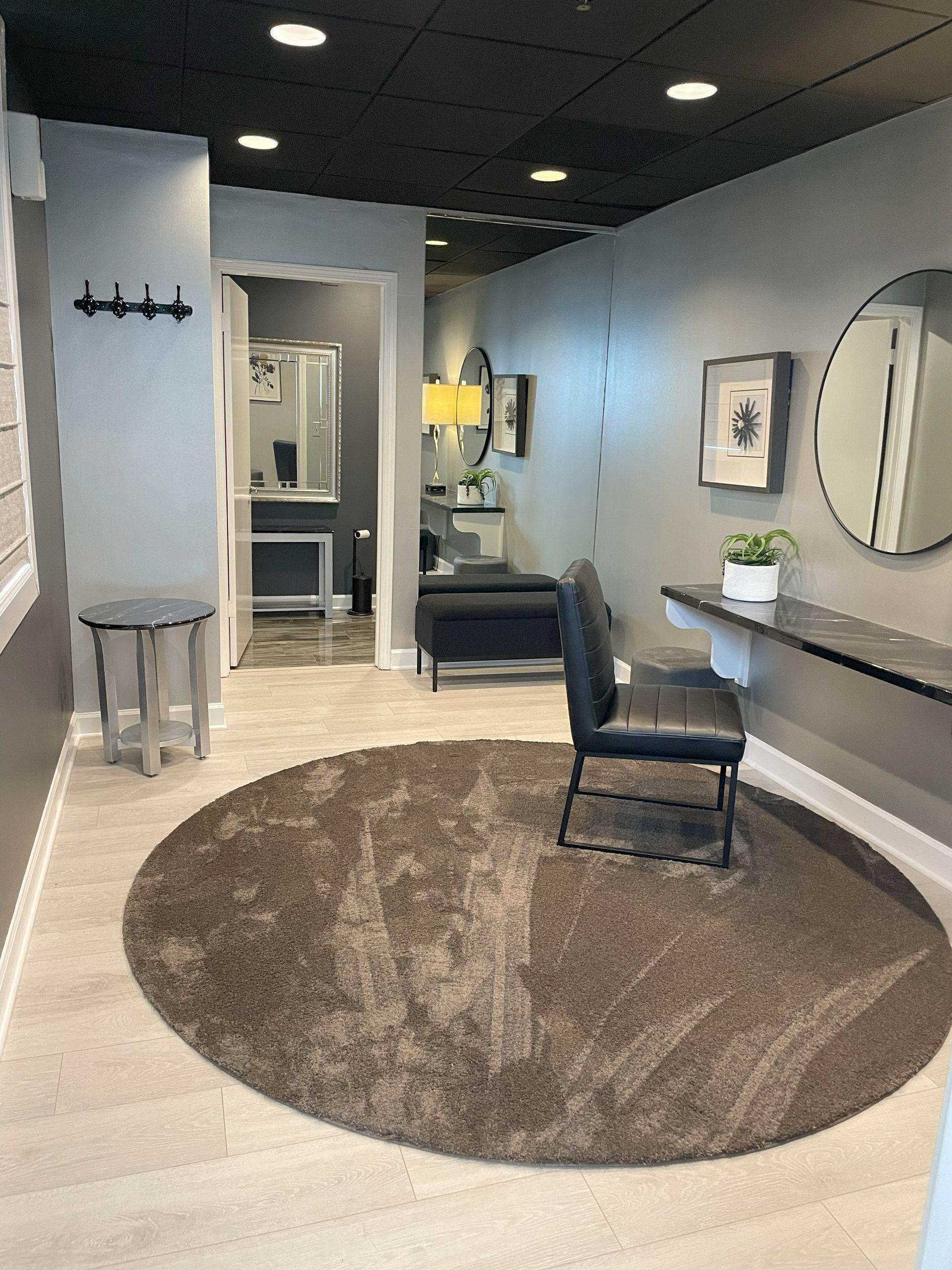 Modern boutique interior with round rug, mirror, bench, plant, and open doorway