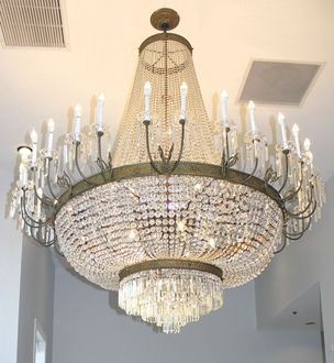 Large ornate crystal chandelier with lit candle-style bulbs hanging from a ceiling indoors