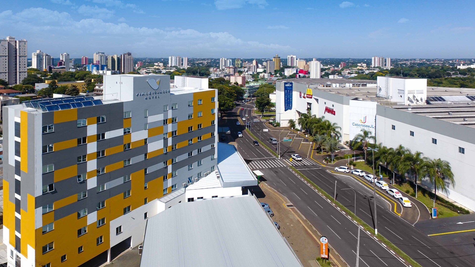 Paisagem urbana com hotéis e prédios comerciais sob um céu azul. Fachadas de edifícios em amarelo, cinza e branco.