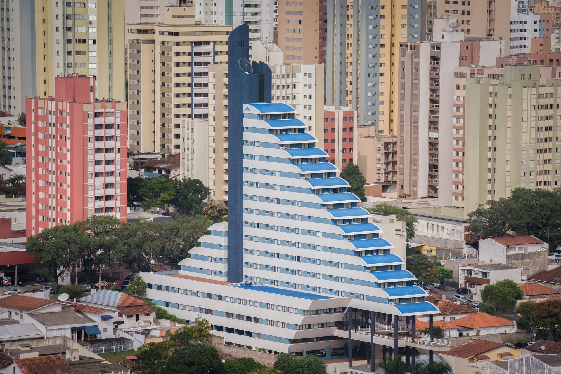 Edifício moderno em degraus, branco e azul, com um cenário de edifícios residenciais coloridos.