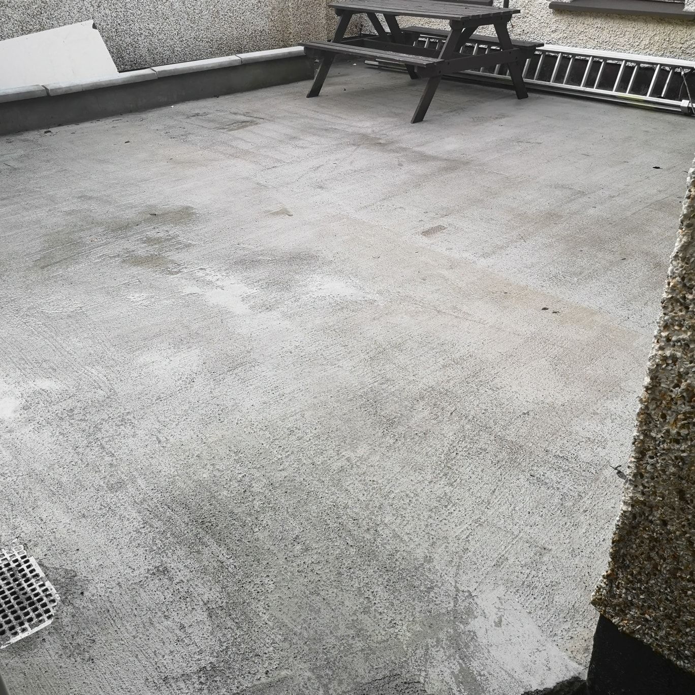 A concrete floor with a picnic table and ladder on it