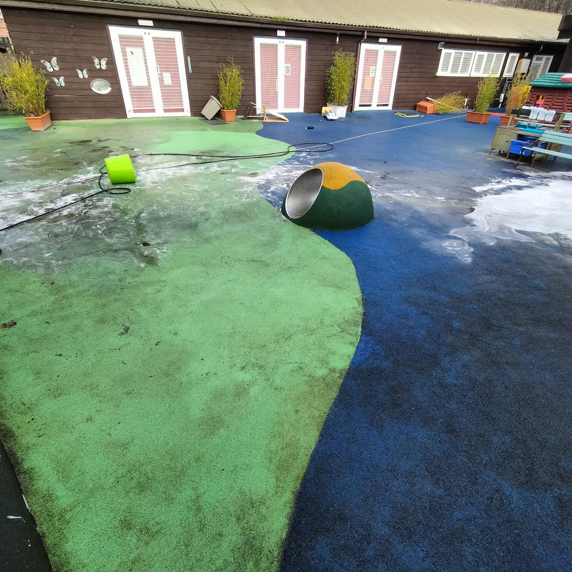 A green and blue playground with a bucket on the ground