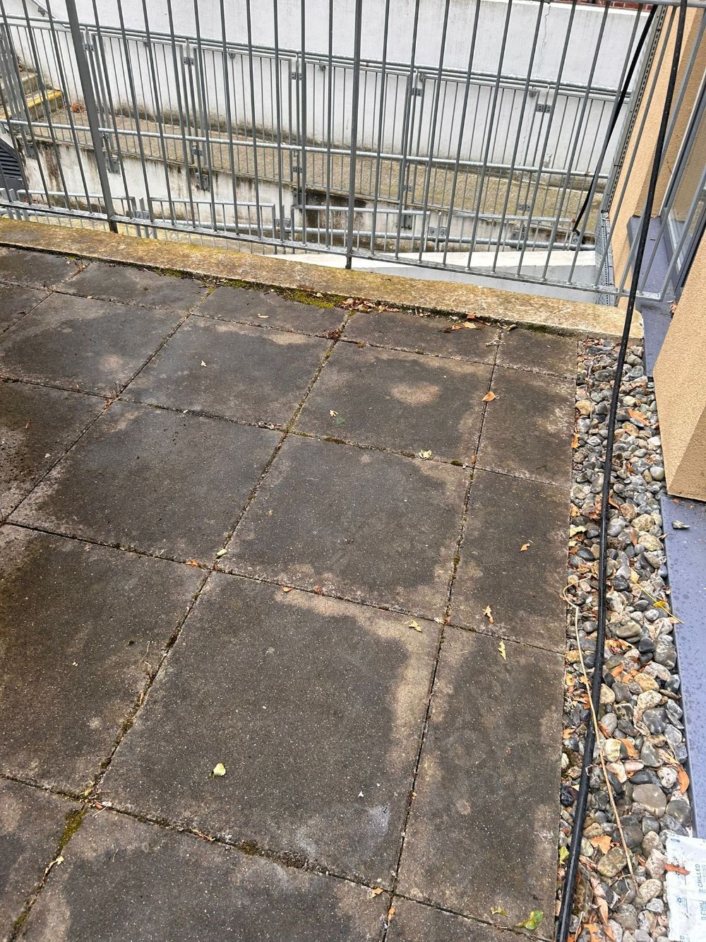 A balcony with a concrete floor and a metal railing.