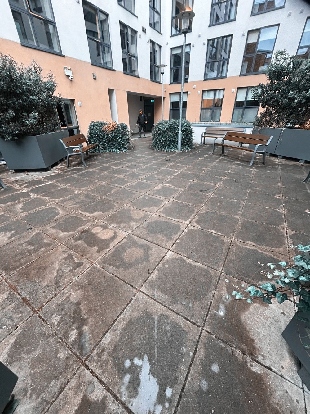 A patio with a bench and planters in front of a building
