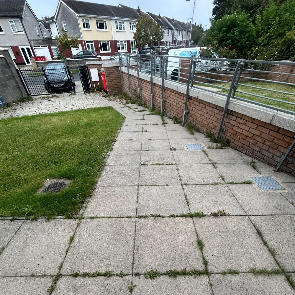 A brick wall surrounds a patio with a car parked in the background.