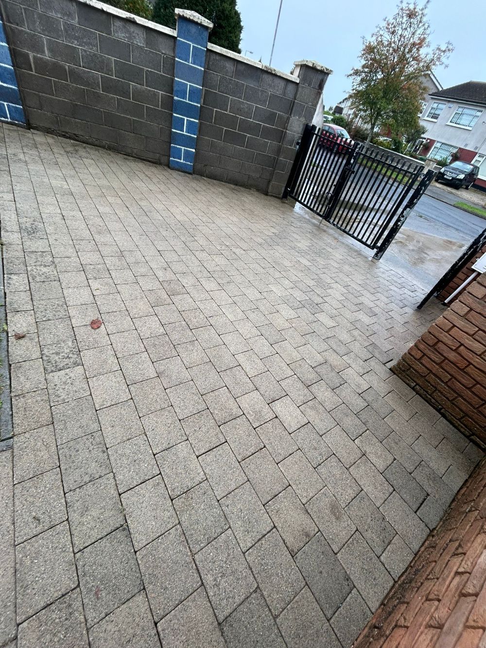 A brick driveway with a fence and a gate in the background.