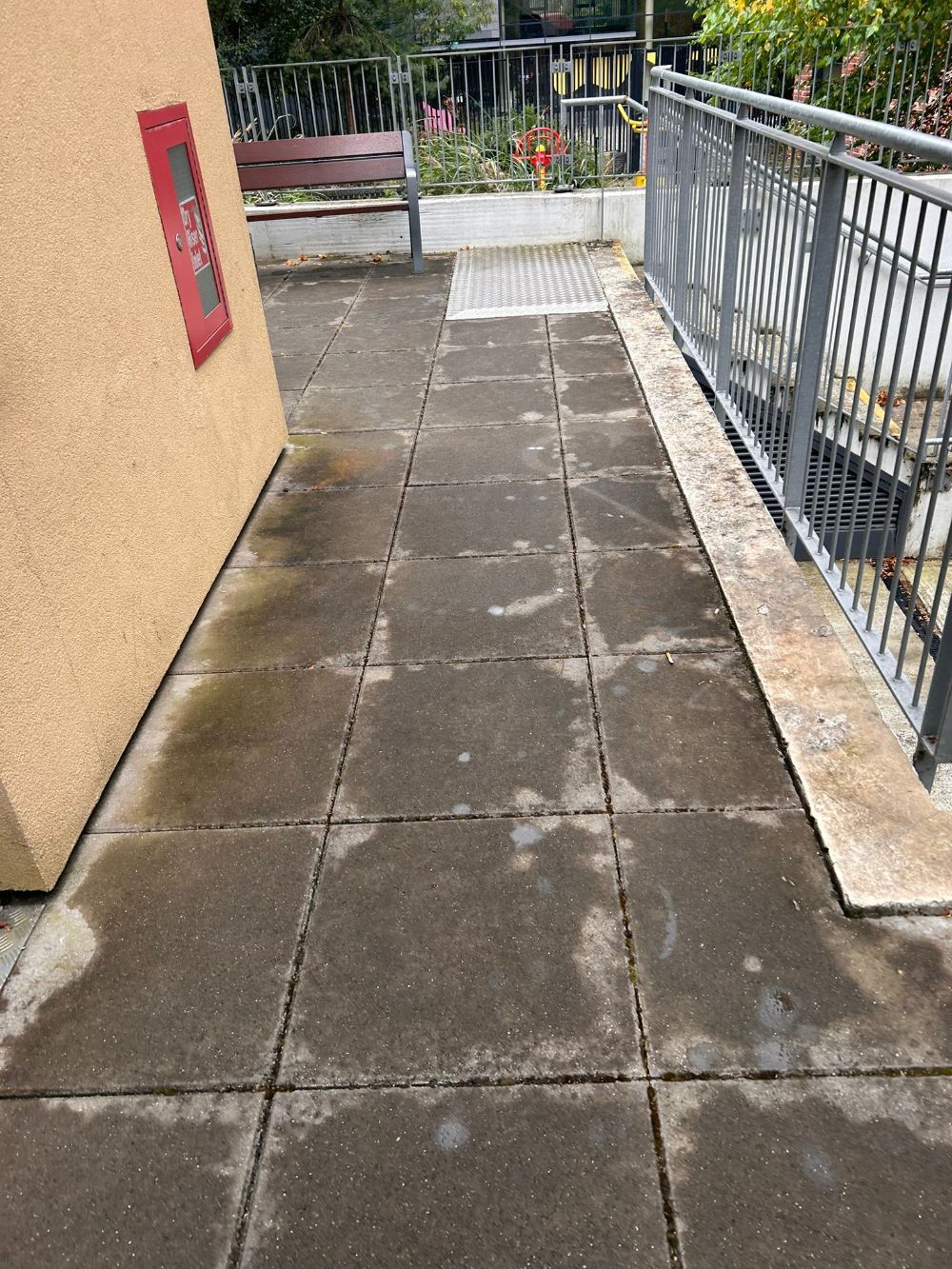 A walkway with a fire extinguisher on the side of a building.