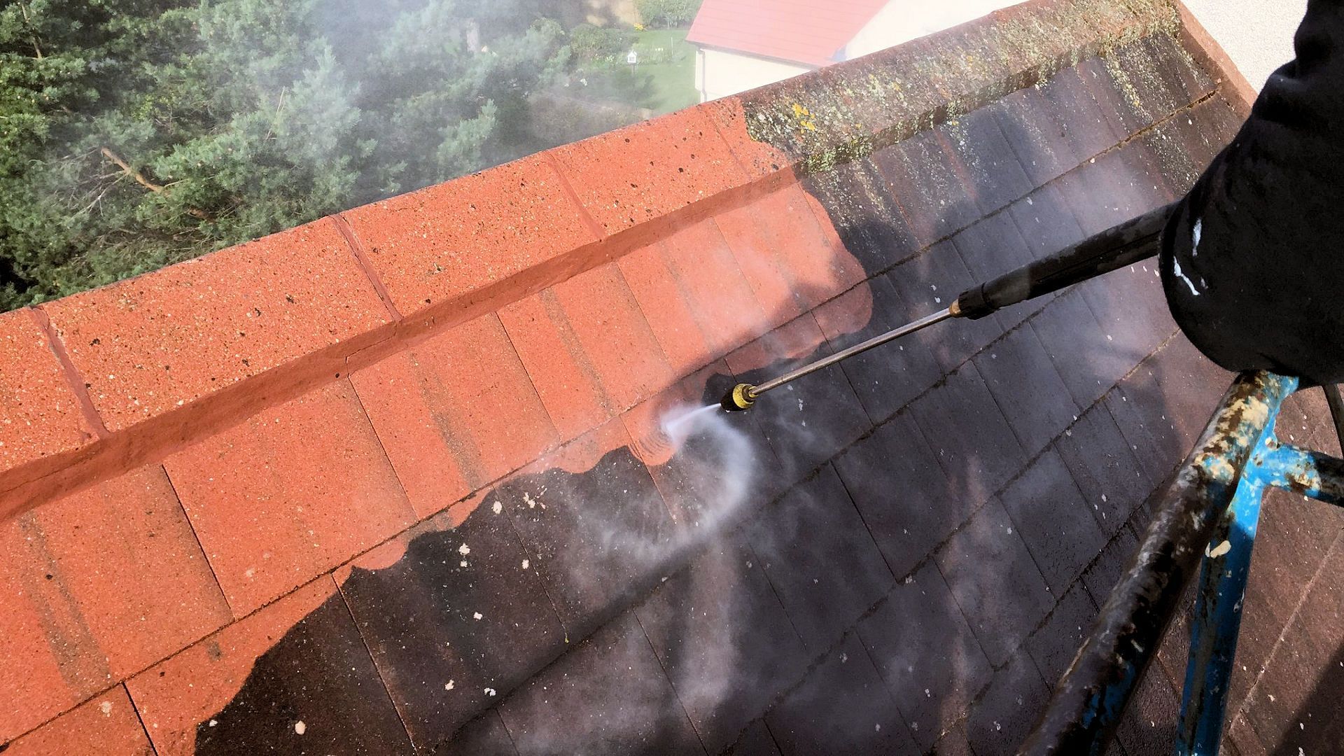A person is using a high pressure washer to clean a brick walkway.