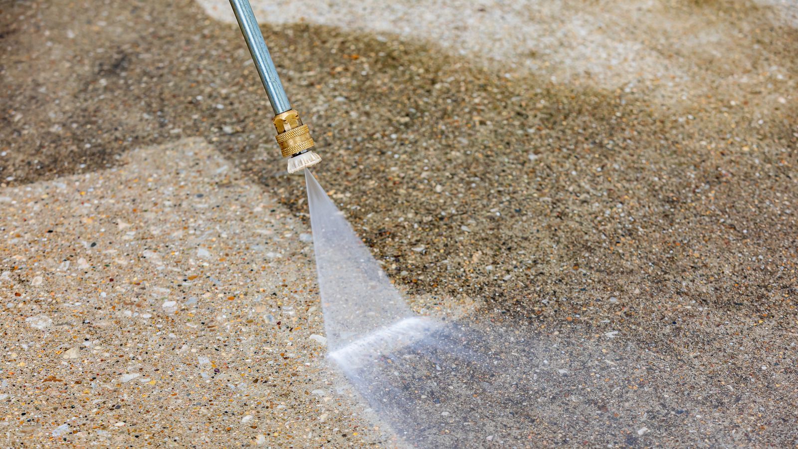 A person is using a high pressure washer to clean a concrete floor.