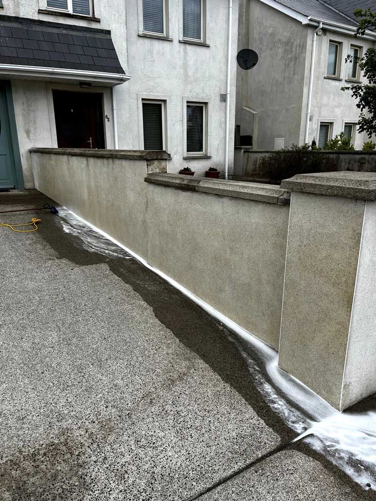 A white house with a concrete wall in front of it.