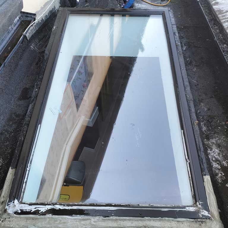 A skylight with a reflection of a building in it