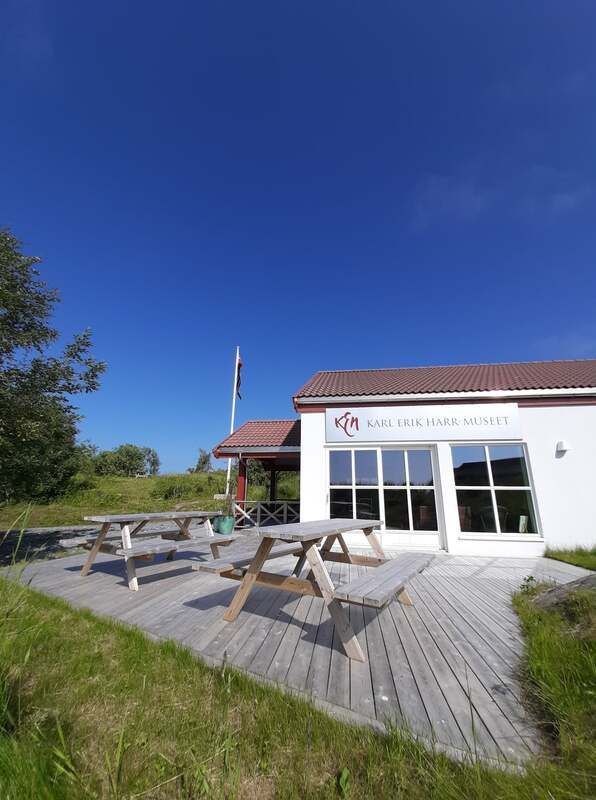 Liten hvit kafé med utendørs piknikbord i tre på en solrik dag under en klar blå himmel