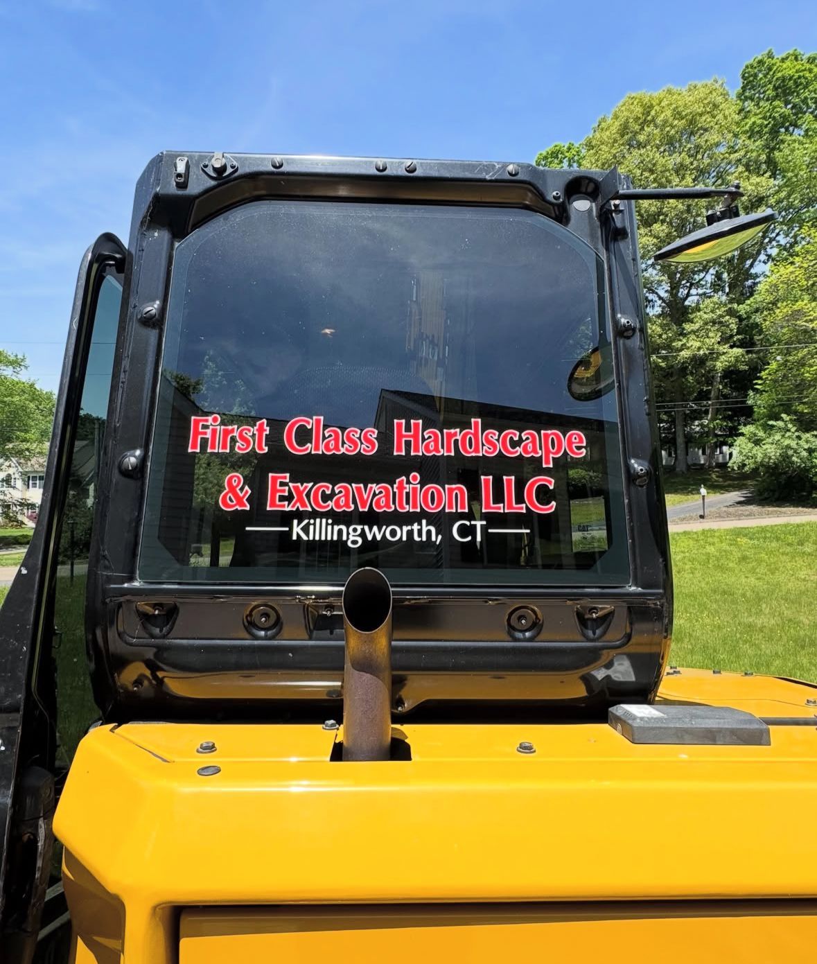 A small white and black excavator inside a garage, with the boom arm extended.