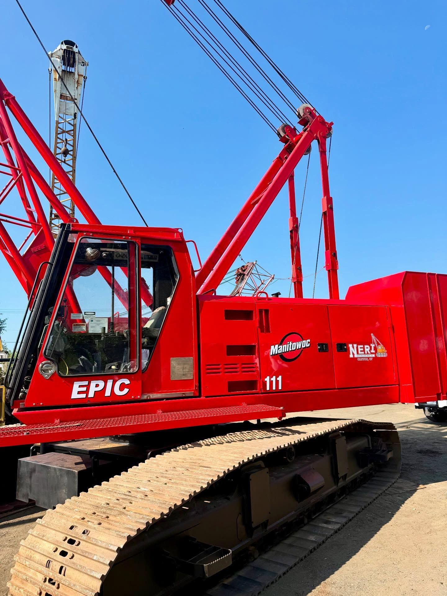 Red EPIC crane on tracks against a clear blue sky.
