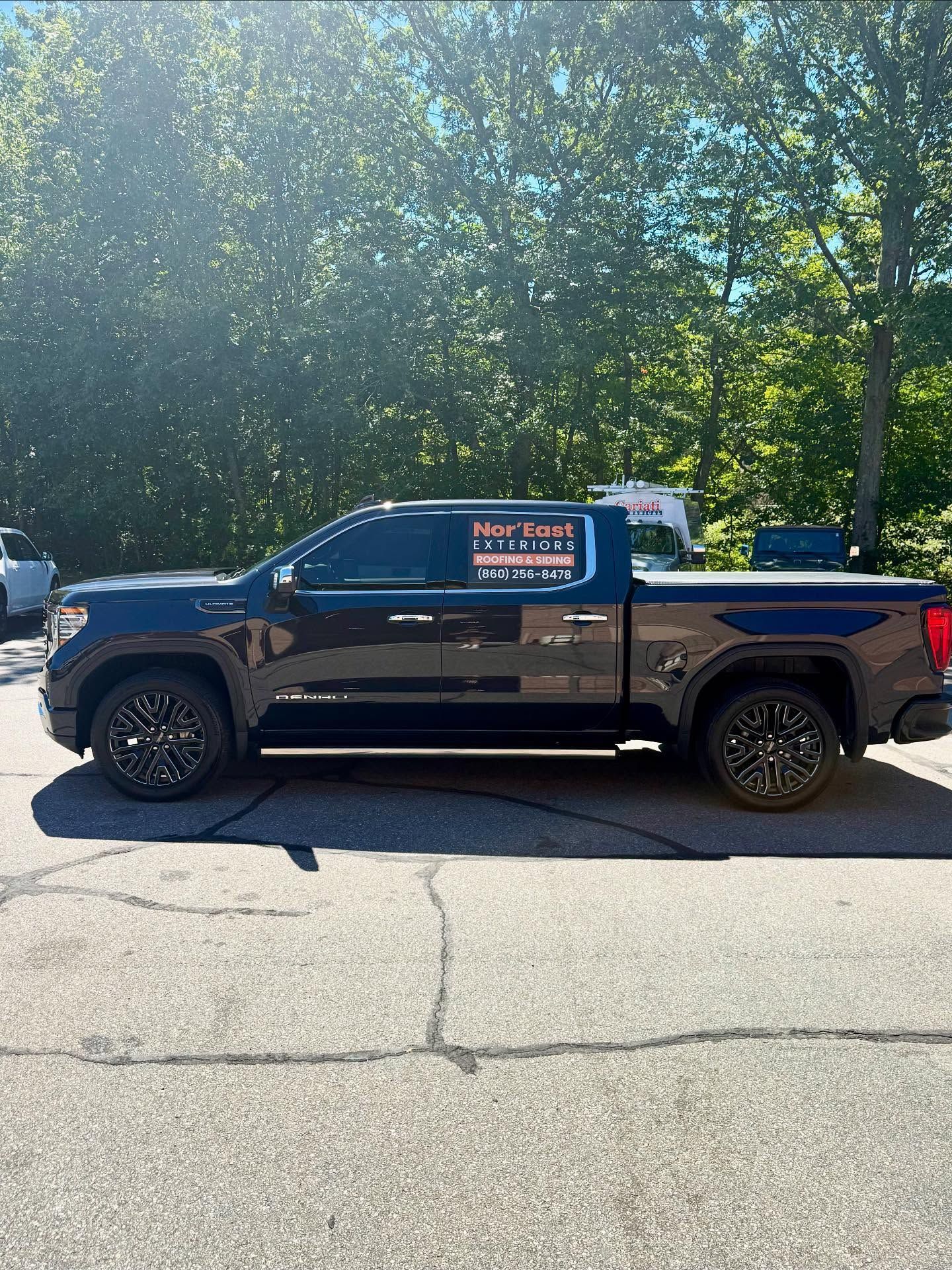 Black pickup truck with tinted windows parked on asphalt; trees in background.