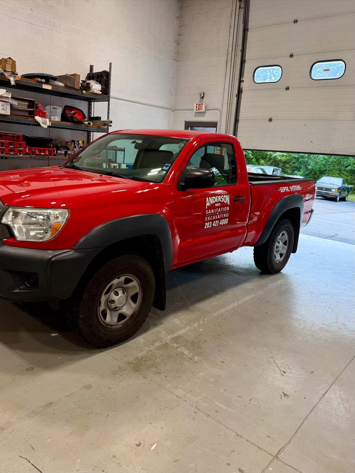 Red Toyota Tacoma truck parked inside a garage.