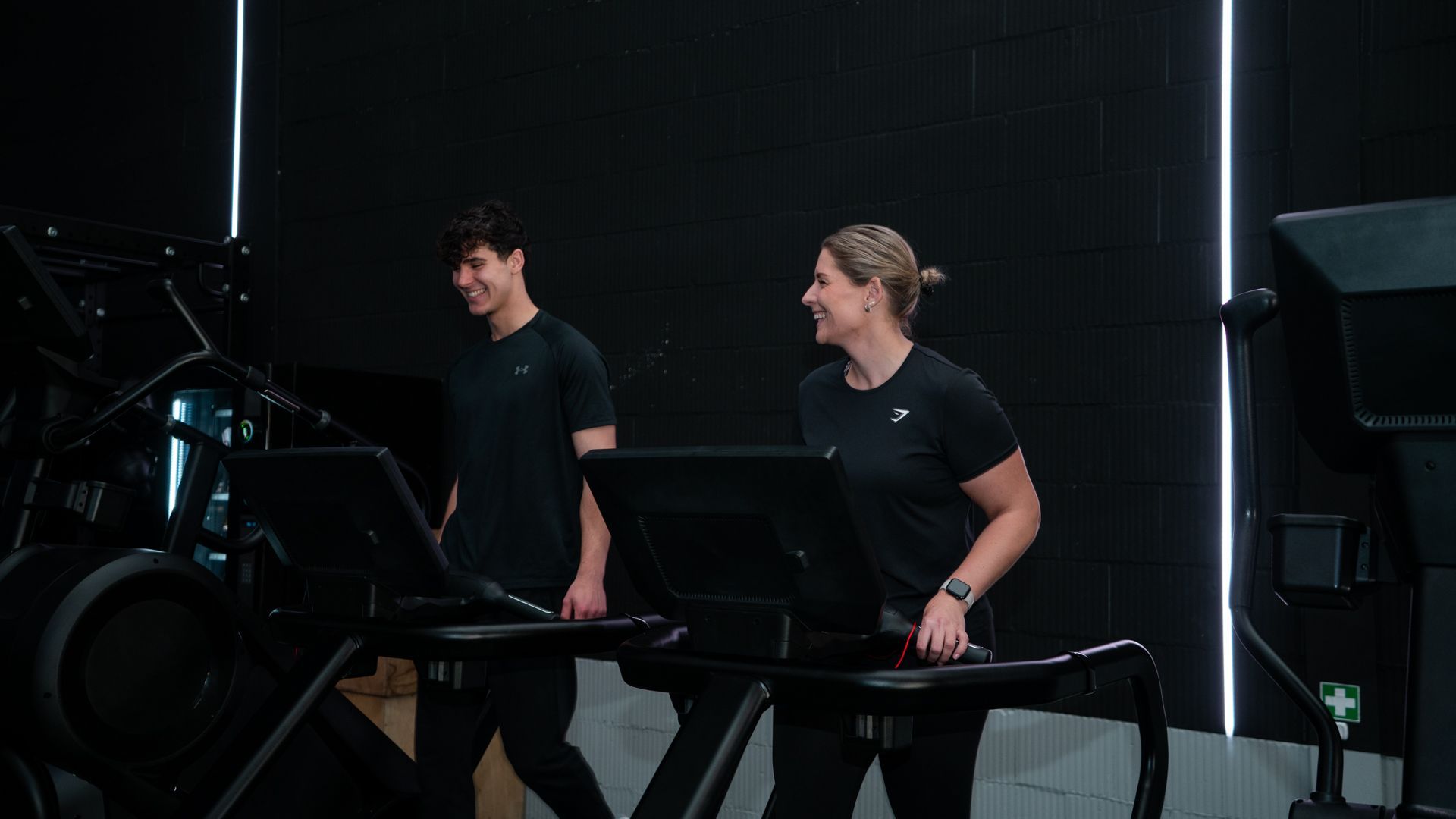Een trainer helpt iemand met het doen van push-ups aan een push-upstang in een sportschool.