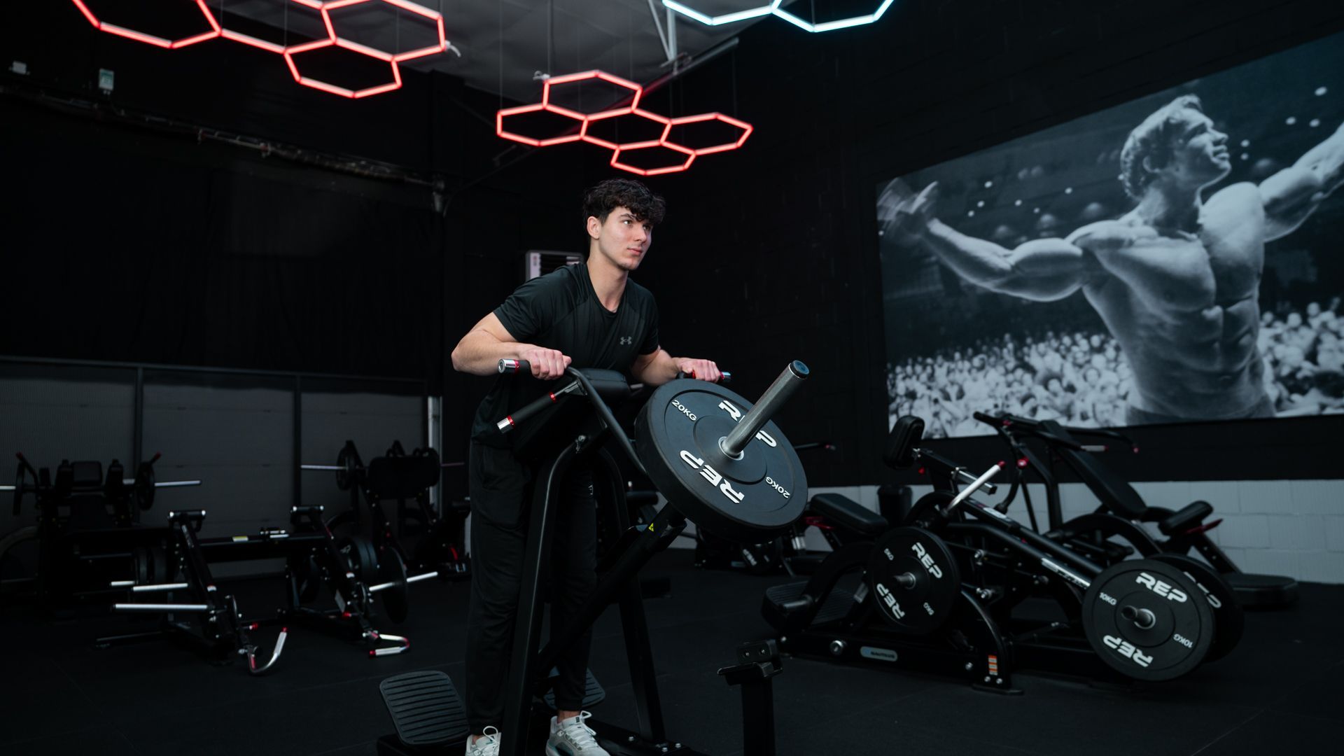 Een persoon tilt een halterstang op in een sportschool, met felgekleurde sportschoenen aan.