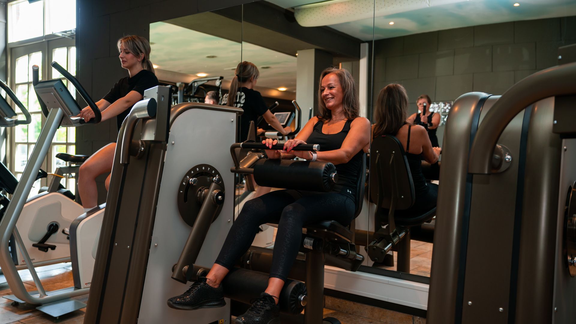 Een trainer helpt iemand met het doen van push-ups aan een push-upstang in een sportschool.