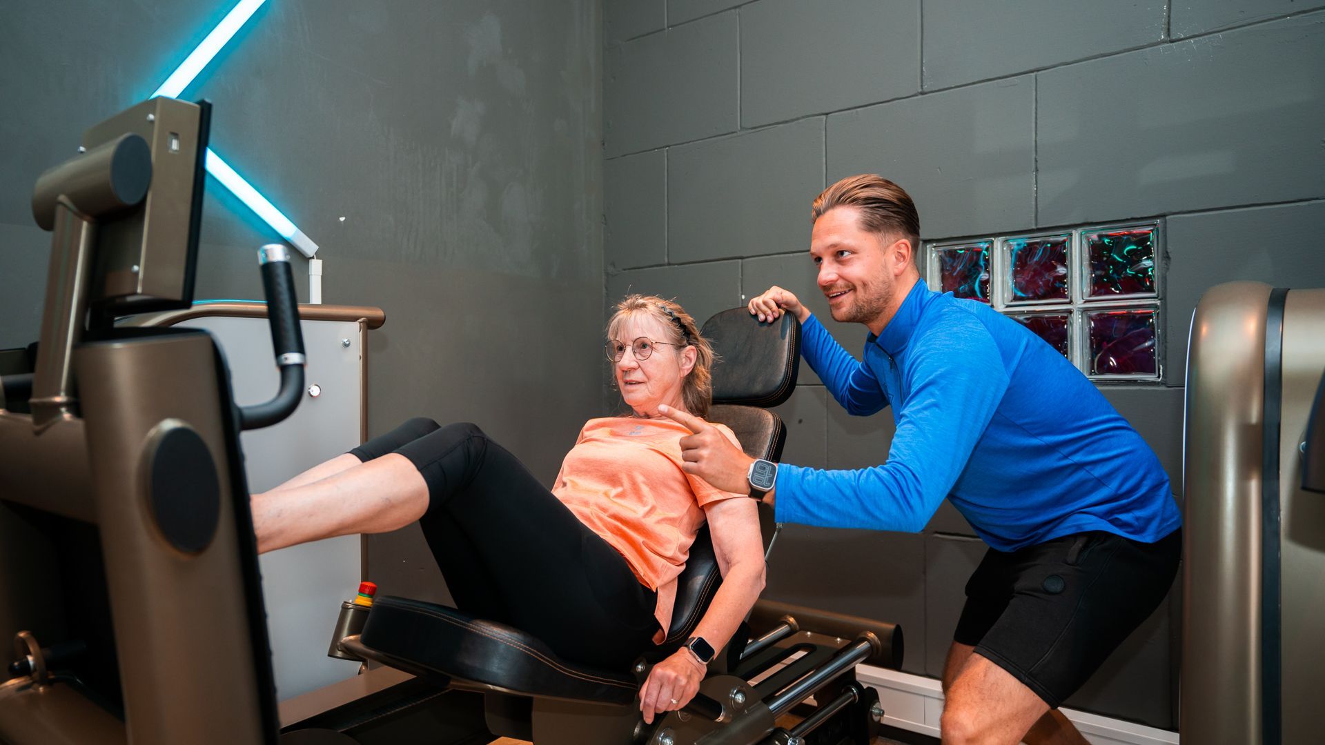 Een man doet een plankoefening op een mat in een schemerige, industriële sportschool.