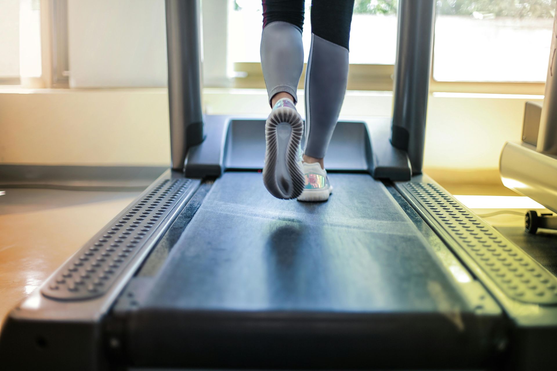 Een persoon loopt op een loopband in een lichte sportschool.