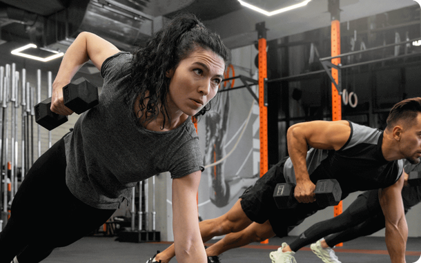 Twee mensen doen plank-push-ups in een moderne sportschool.