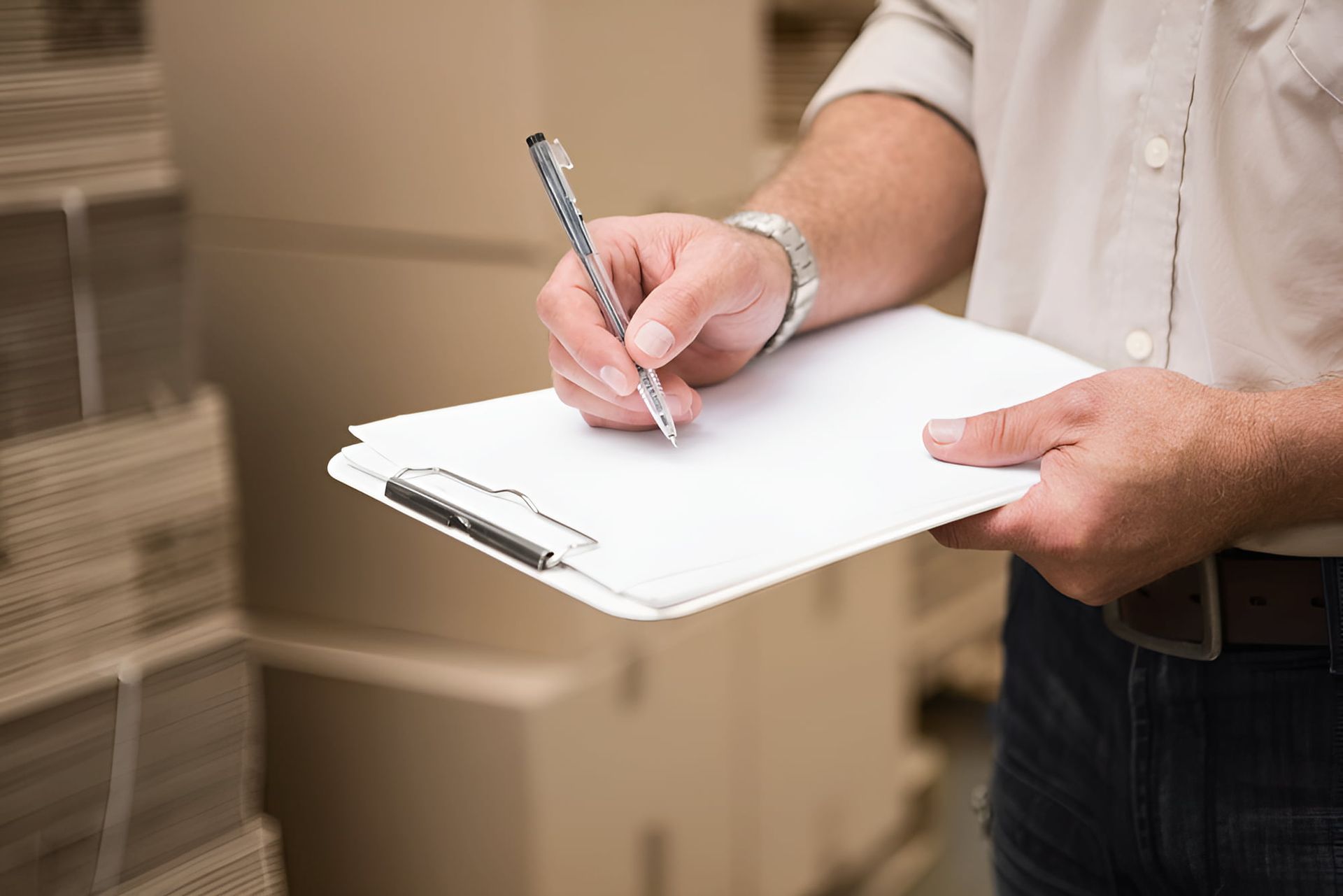 A Man Is Writing On A Clipboard With A Pen — Dawson Moving & Storage NQ In Mount St John, QLD