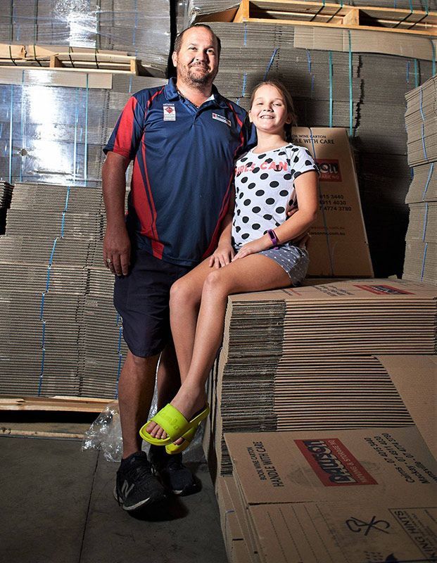 A Man And A Girl Are Standing Next To Each Other In A Warehouse — Dawson Moving & Storage NQ in Townsville, QLD