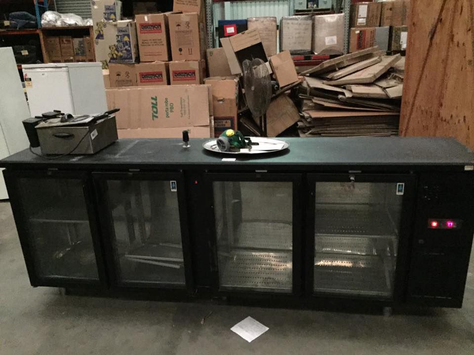 A Black Refrigerator With Glass Doors In A Warehouse Storage — Dawson Moving & Storage NQ in Mount St John, QLD