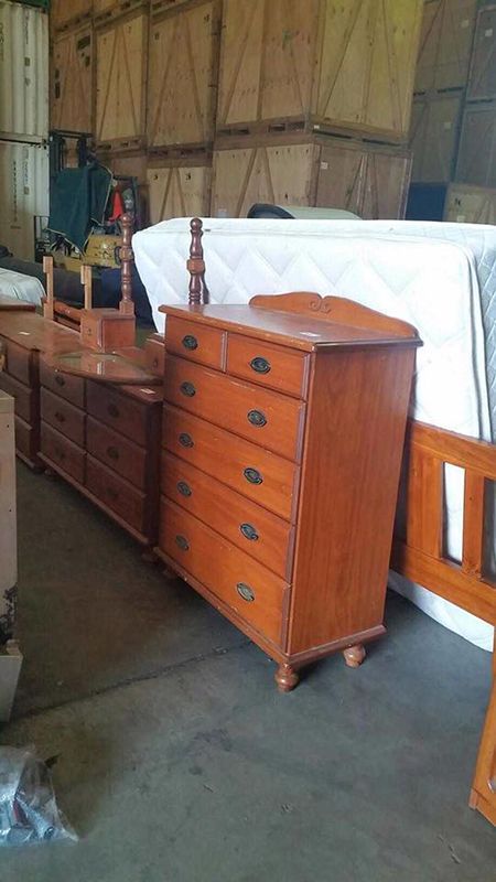 A Row of Wooden Dressers and A Bed in A Warehouse — Dawson Moving & Storage NQ in Townsville, QLD