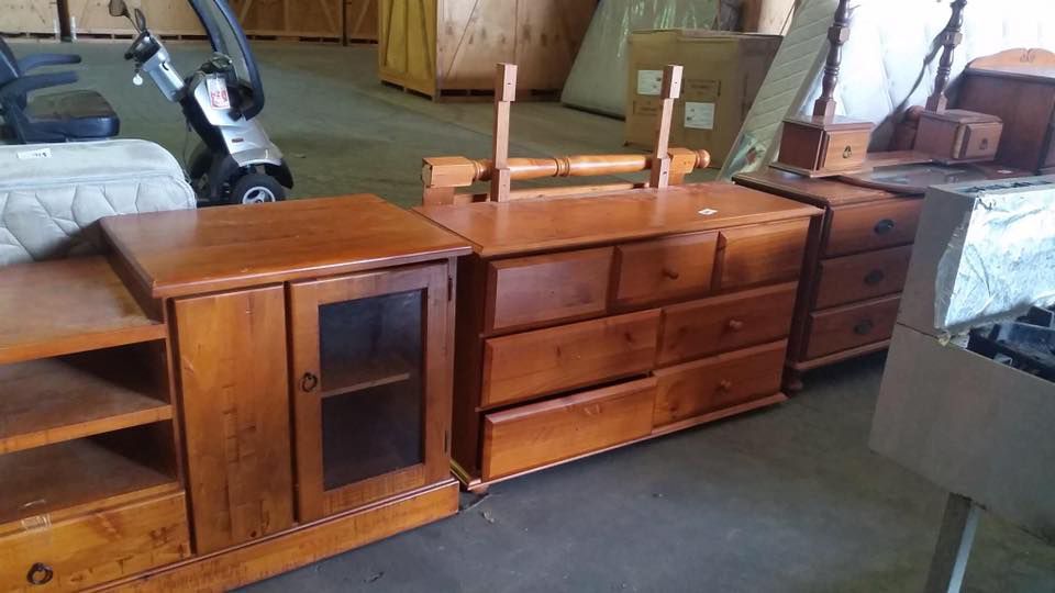 A Row Of Wooden Furniture In A Warehouse With A Golf Cart In The Background — Dawson Moving & Storage NQ in Mount St John, QLD
