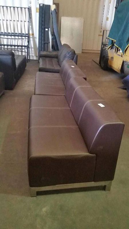 A Row Of Brown Leather Couches Are Sitting In A Warehouse — Dawson Moving & Storage NQ in Townsville, QLD