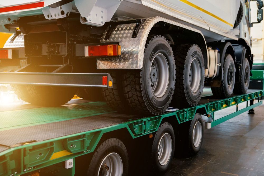 A Dump Truck Is Sitting On Top Of A Trailer — Dawson Moving & Storage NQ in Mount St John, QLD