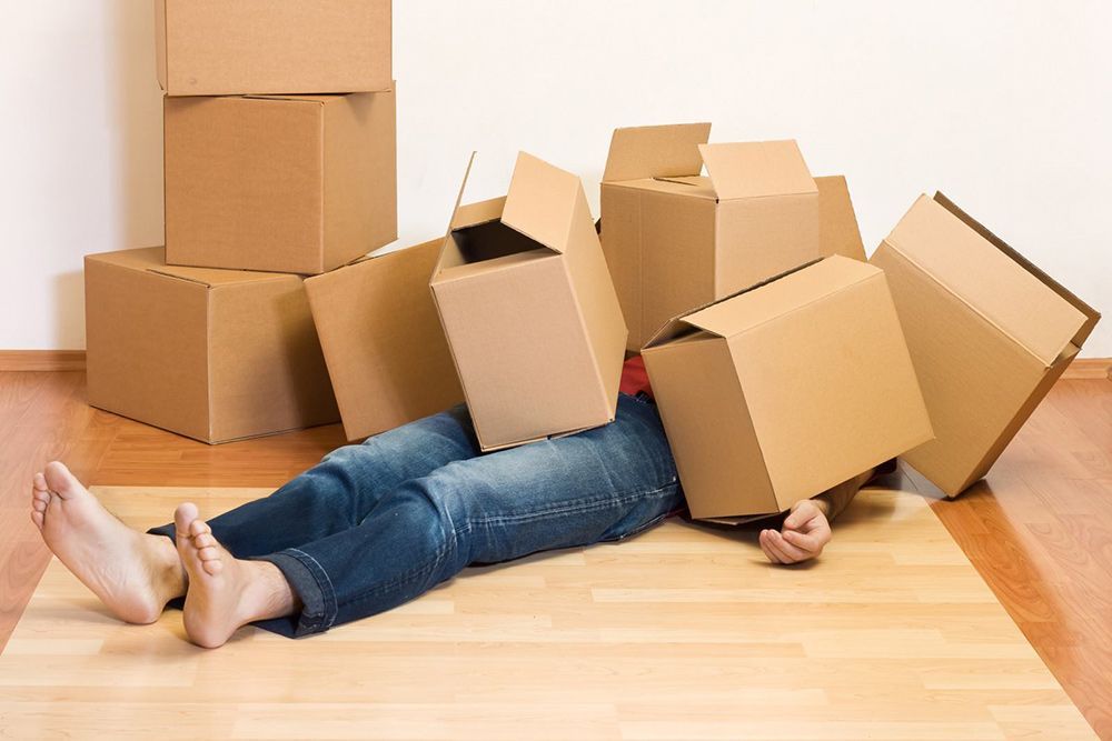A Person Is Laying On The Floor With Cardboard Boxes On Their Head — Dawson Moving & Storage NQ in Mount St John, QLD
