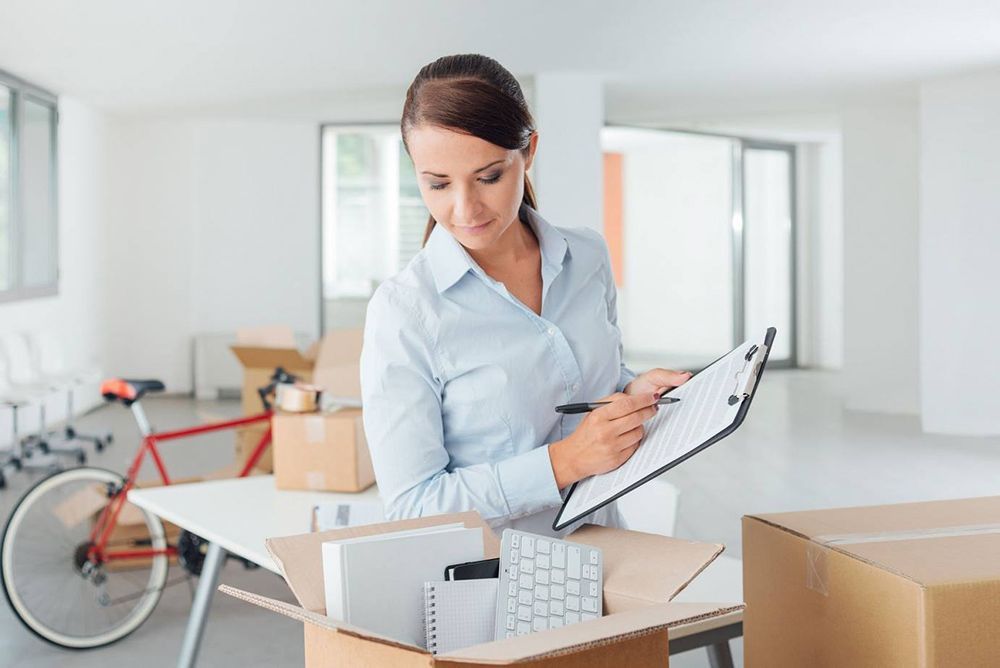 Woman Holding A Clipboard With A Relocation Checklist With Moving Boxes In The Background — Dawson Moving & Storage NQ in Melbourne, VIC