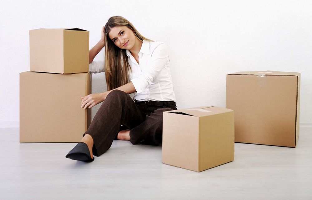 A Woman Is Sitting On The Floor With Cardboard Boxes — Dawson Moving & Storage NQ in Mount St John, QLD