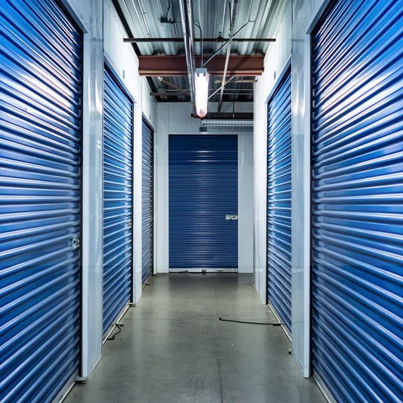 A Hallway Filled With Blue Garage Doors And A Light Hanging From The Ceiling — Dawson Moving & Storage NQ in Townsville, QLD