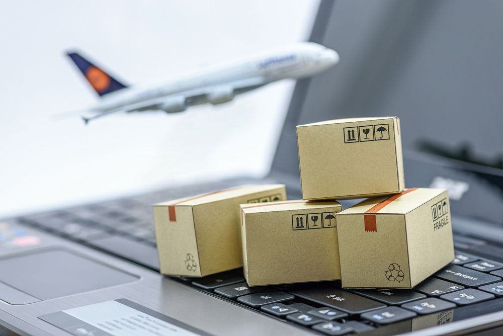 A Stack Of Cardboard Boxes Sitting On Top Of A Laptop Keyboard With An Airplane In The Background — Dawson Moving & Storage NQ in Rockhampton, QLD