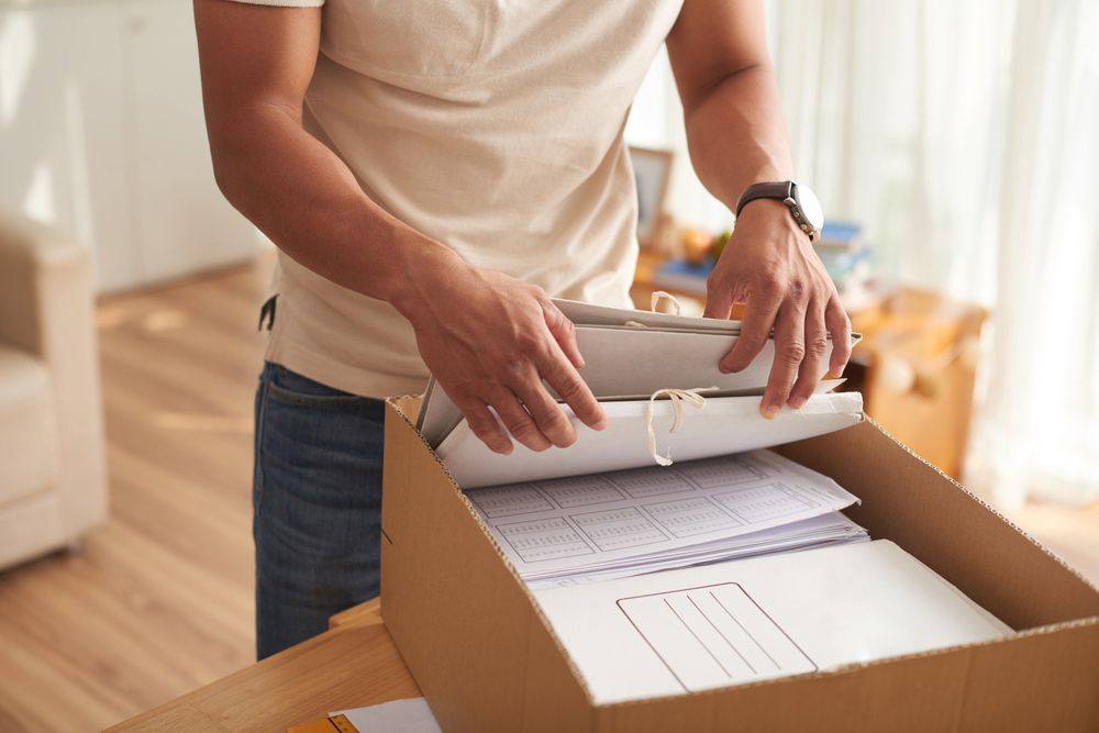 A Man Is Opening a Cardboard Box Filled with Papers — Dawson Moving & Storage NQ in Gladstone, QLD