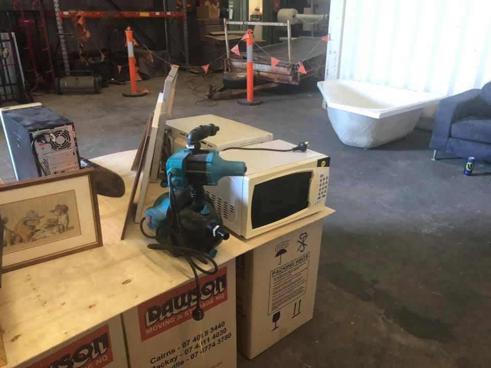 A Microwave Oven Is Sitting On Top Of A Cardboard Box In A Warehouse — Dawson Moving & Storage NQ in Townsville, QLD