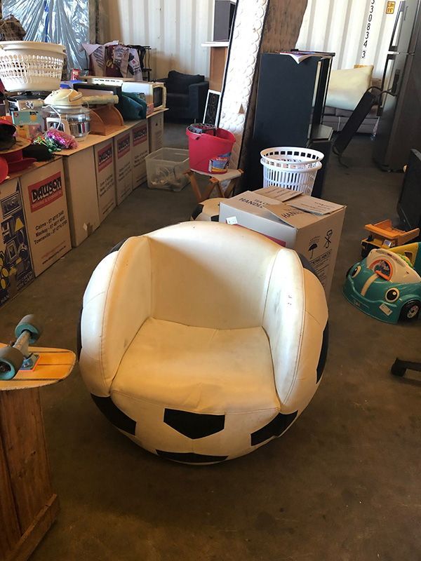 A Chair In The Shape Of A Soccer Ball Is Sitting In A Room Filled With Boxes — Dawson Moving & Storage NQ in Bowen, QLD