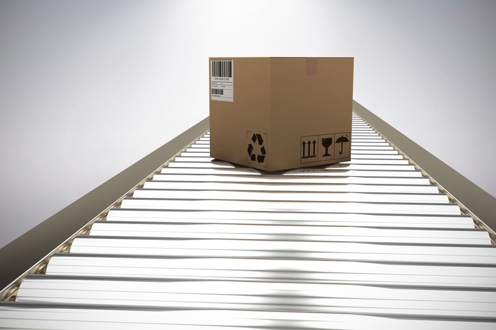 A Cardboard Box Is Sitting On Top Of A Conveyor Belt — Dawson Moving & Storage NQ in Bowen, QLD