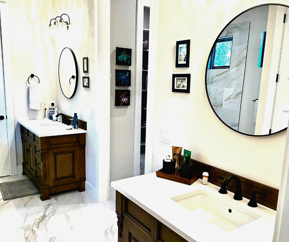 Two bathroom vanities with white countertops and dark wood cabinets. One with a round mirror, one with an oval mirror.