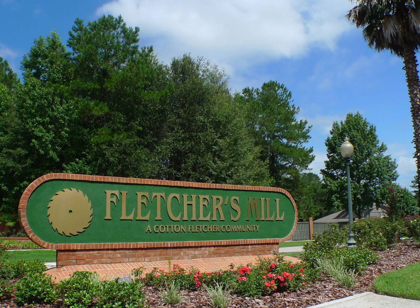 Sign for Fletcher's Mill, a gated community, featuring a green and brown sign with a saw blade emblem.