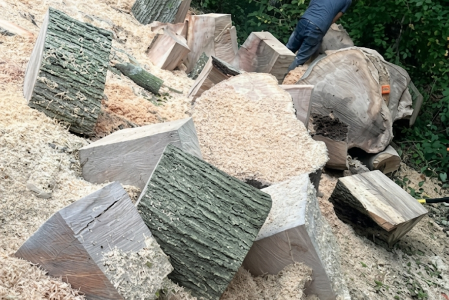 Broken stone slabs and sawdust on the ground, with a worker’s legs visible in the background.