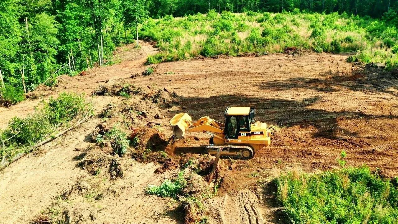 Land clearing in Dover DE — yellow bulldozer moving dirt and grading a large lot
